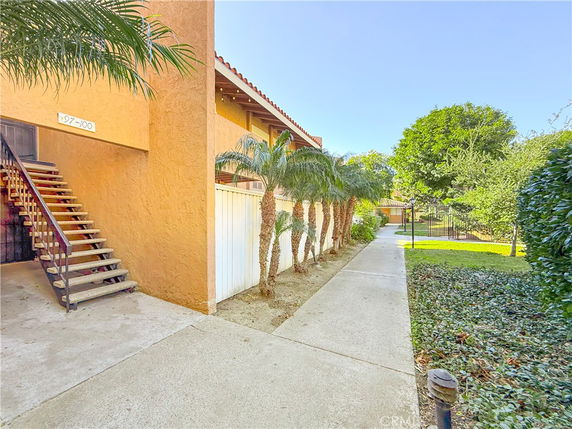 Exterior view of a building with a staircase and walkway, surrounded by plants and trees.