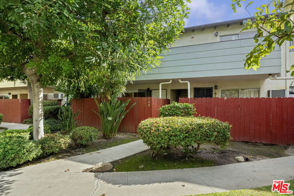 Front view of a two-story residential building with a red fence.