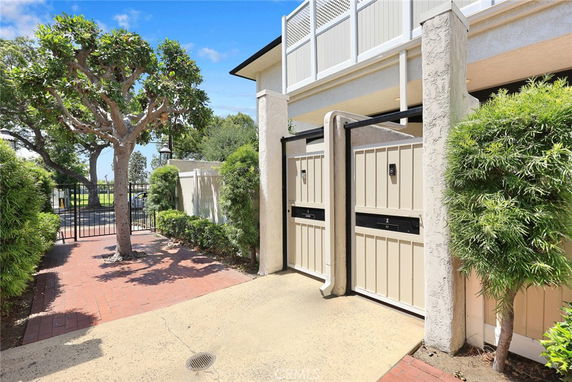 Front view of a building entrance with wooden gates and a pathway surrounded by greenery.
