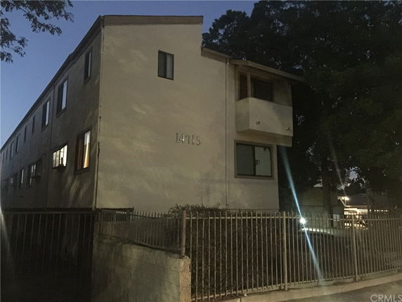 Front view of a multi-story building with windows and a small balcony.