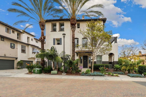 Front view of a two-story house with palm trees and a landscaped front yard.