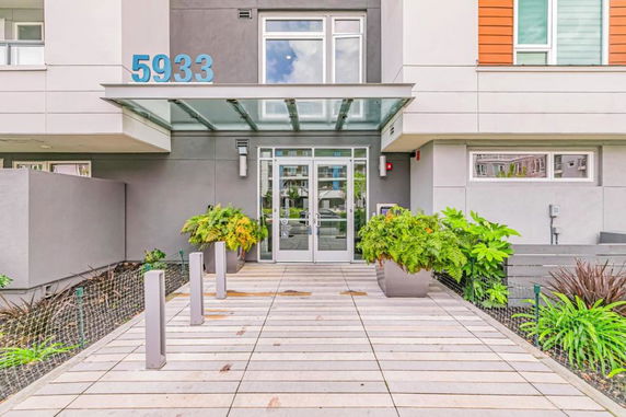 Front view of a modern building entrance with large glass doors and a canopy.