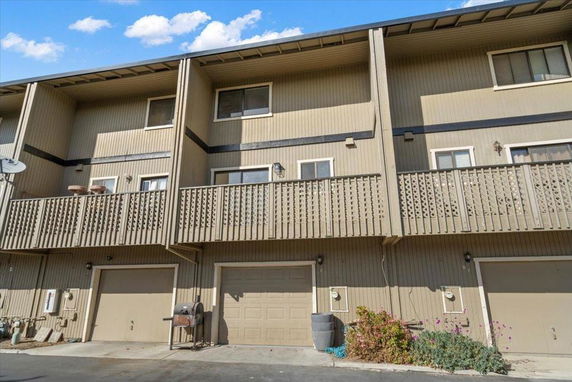 Front view of a multi-story townhouse with balconies and garages.