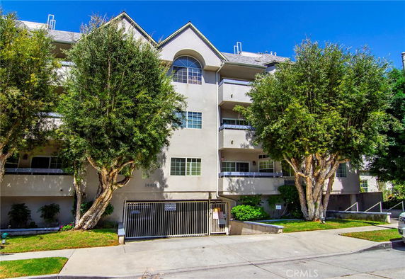 Front view of a multi-story residential building with trees in front.