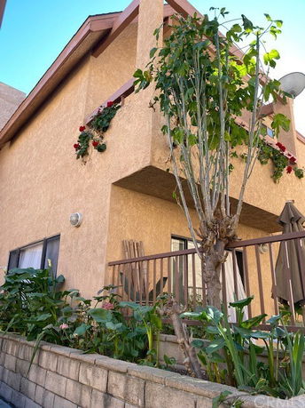 Front view of a two-story house with a small balcony and decorative plants.