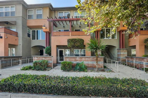 Front view of a multi-story residential building with balconies and landscaped entrance.