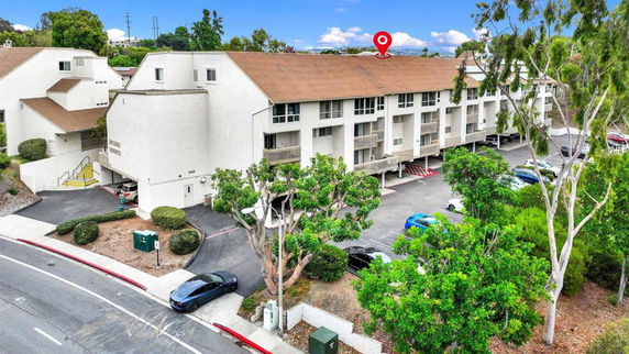 Front view of a multi-story residential building with parking spaces underneath.