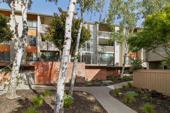 Front view of a multi-story residential building with balconies and brick accents.