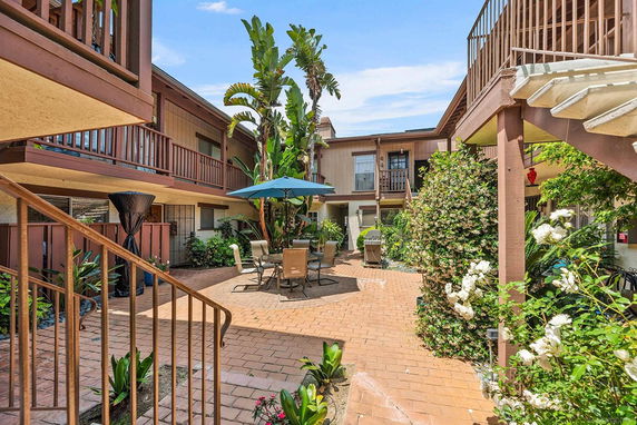 Courtyard view of an apartment complex with outdoor seating and plants.