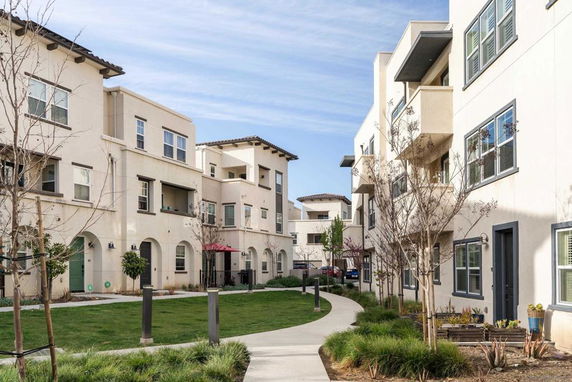 Front view of multi-story apartment buildings with balconies and arched entrances.