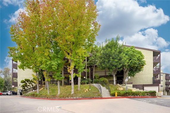 Front view of a multi-story residential building surrounded by trees.