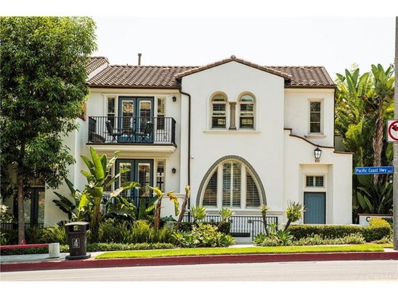 Front view of a two-story house with a balcony and arched windows.