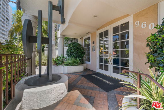 Front view of a building entrance with double glass doors and a metal sculpture.