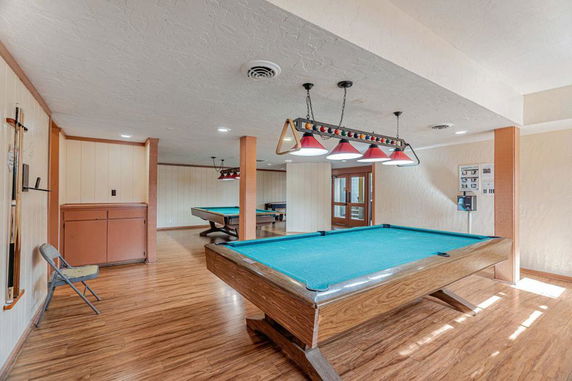 Interior room with billiard tables and wooden flooring.