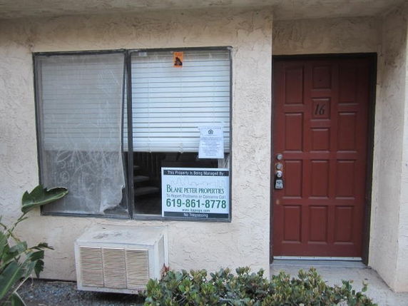 Front view of a building with a red door and a window with blinds.