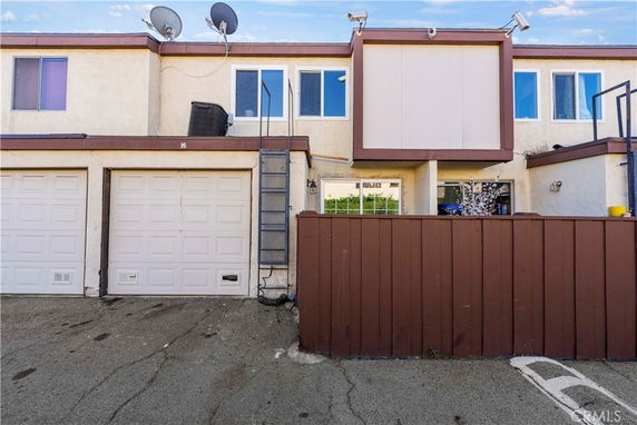 Front view of a two-story building with garages and a fence.