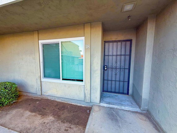 Front view of a house with a metal security door and a window with blinds.