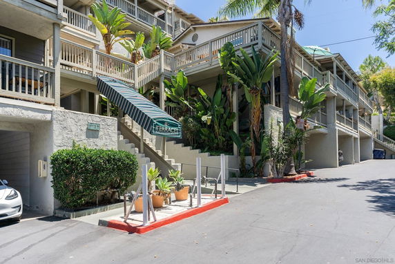 Front view of a multi-story building with balconies and greenery.
