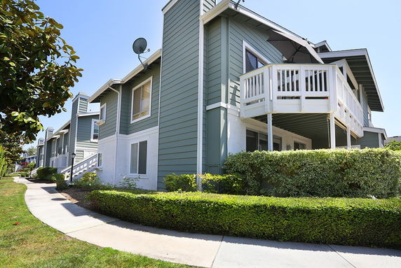 Front view of a multi-story residential building with balconies and green siding.