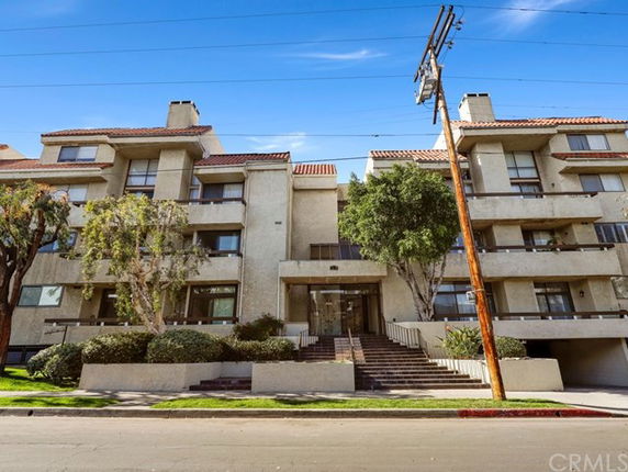 Front view of a multi-story residential building with balconies and staircases.