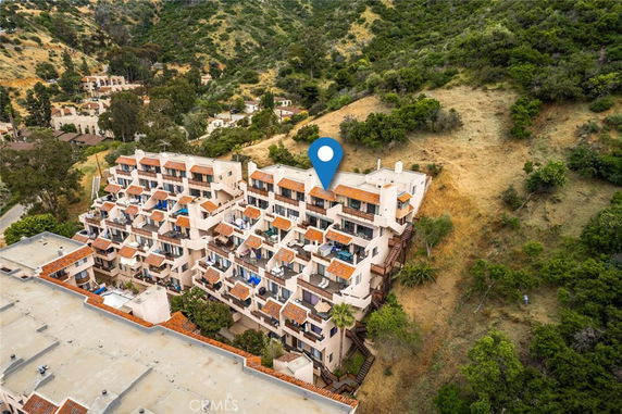 Aerial view of a multi-story building complex nestled in hilly terrain.