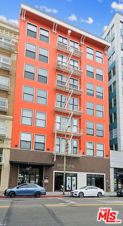 Front view of a multi-story building with orange facade and fire escape.