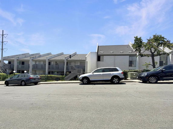 Front view of a multi-story building with unique angular roof design and balconies.