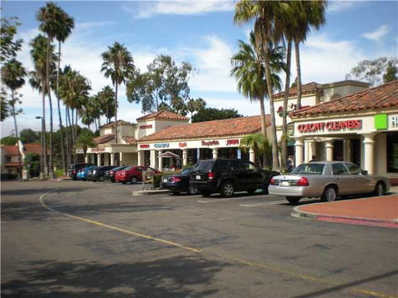 Outdoor parking area in front of a row of shops.