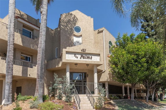 Front view of a multi-story building with a balcony and circular window design.