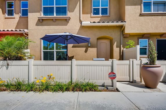Front view of a multi-story townhouse with a small fenced patio.