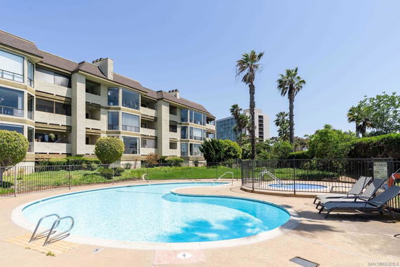 View of an outdoor swimming pool area with adjacent multi-story residential buildings.