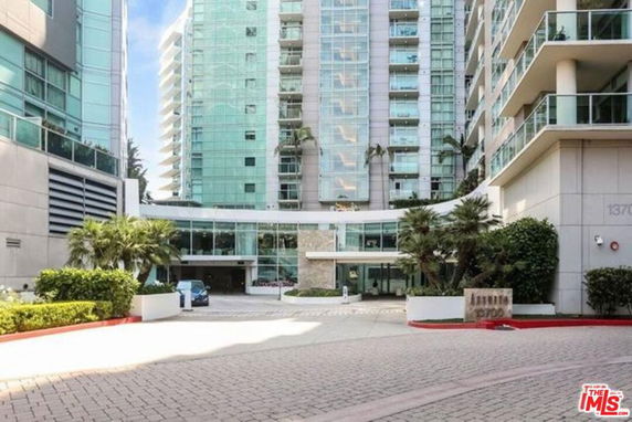 Front view of a modern multi-story apartment building with glass balconies.