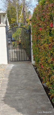 Iron gate entrance with a walkway and hedge.