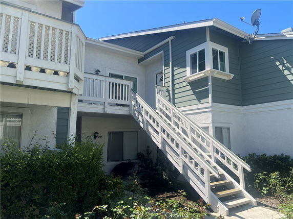 Front view of a two-story building with exterior staircase and balcony.