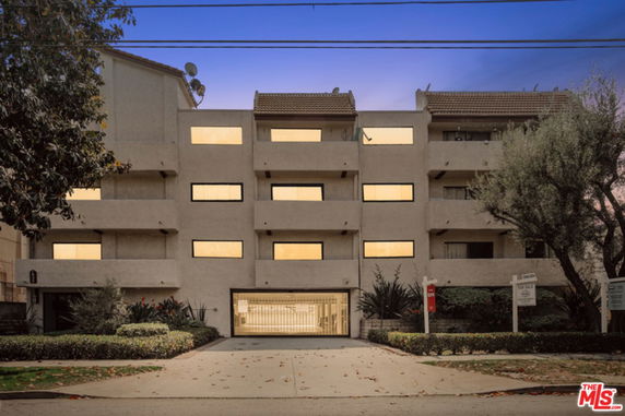 Front view of a multi-story apartment building with a gated entrance.