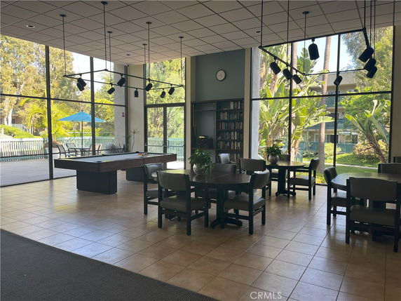 Interior view of a clubhouse with seating areas, a pool table, and large glass windows.