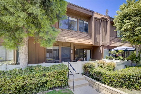 Front view of a two-story townhouse with brown wooden siding and a small front garden.