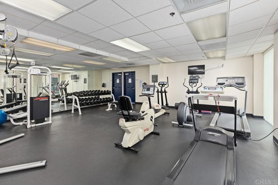 Indoor gym area with exercise equipment and mirrored wall.