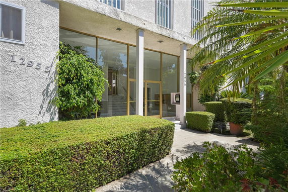 Front view of a building with large glass doors and surrounding greenery.