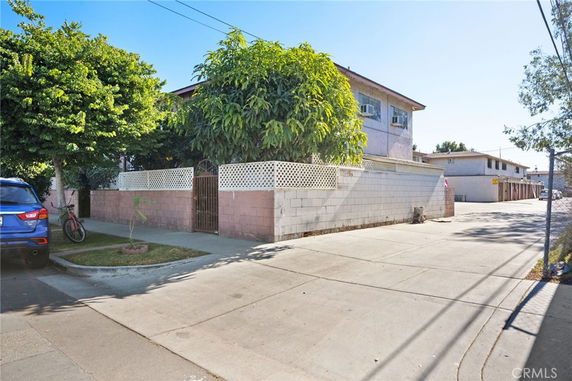 Front view of a two-story building with a brick wall and gate.