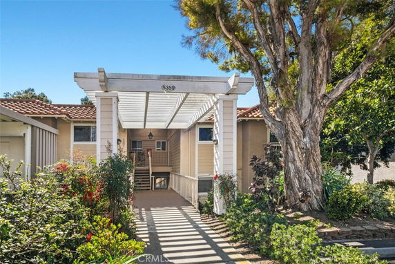 Front view of a house with a pergola entrance and a red-tiled roof.