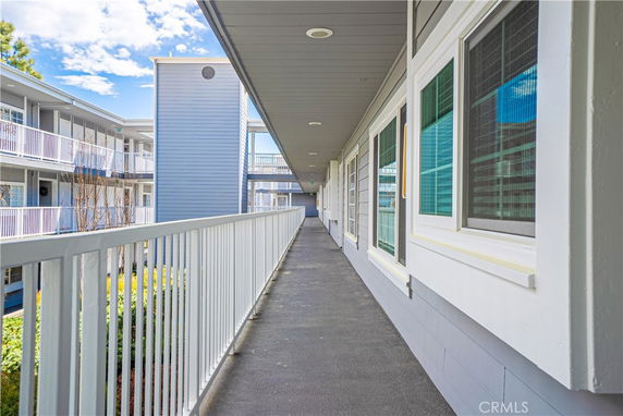 Exterior walkway of a multi-story building with white railings and a blue facade.