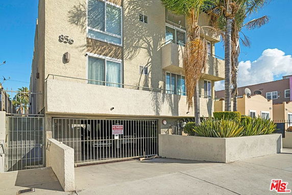 Front view of a multi-story residential building with balconies and gated parking.