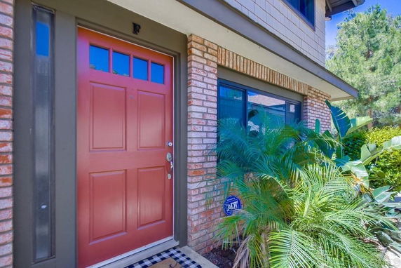 Front view of a house entrance with a red door and brick exterior.