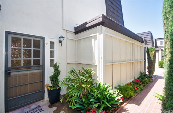 Front view of a house entrance with decorative plants and a pathway.