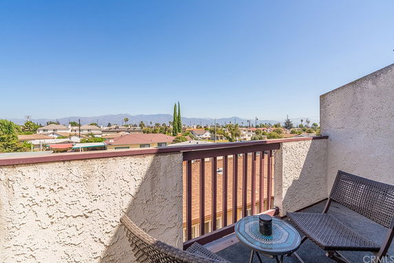 View from a balcony showing rooftops and distant mountains.