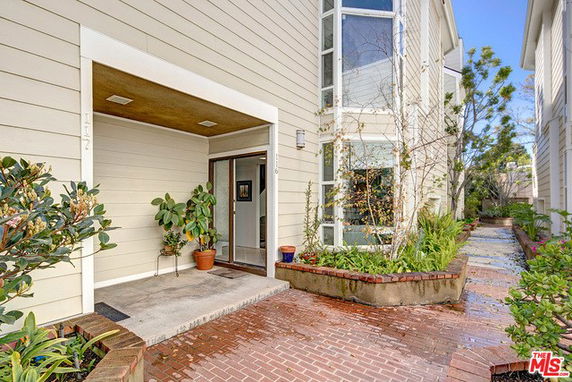 Front view of a building entrance with pathway and potted plants.