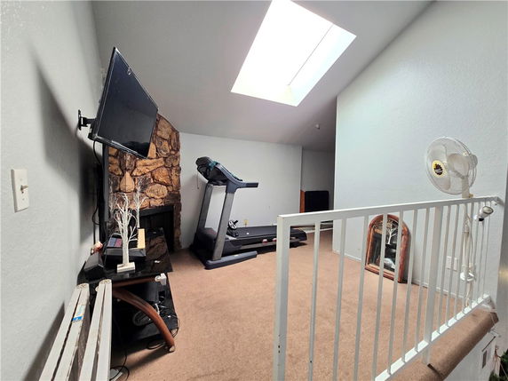 Indoor space with a treadmill, TV, and a skylight.