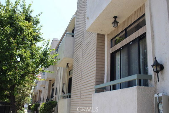 Front view of a multi-story building with balconies and exterior lights.