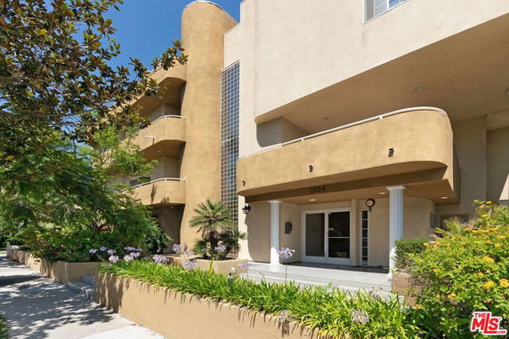 Front view of a multi-story building with balconies and a glass block feature.